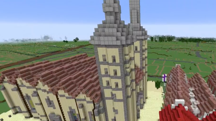 Ein Minecraft-Gebäude mit roten Dächern und einem hohen Turm in ländlicher Umgebung.