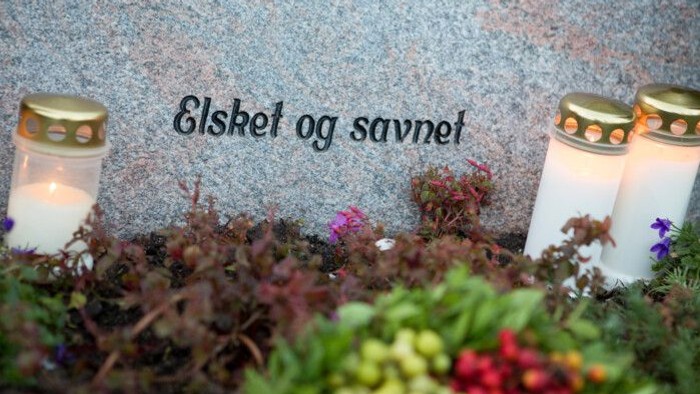 To candler, blomster og en gravsten med indgraveret