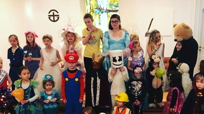Gruppe af børn og voksne i festlige kostumer, der glædeligt poser til et Halloween-tema-foto.