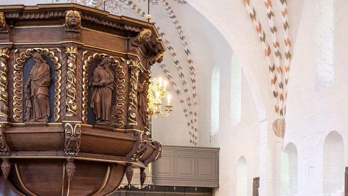 Indre del af kirke med altertavle og bænke.