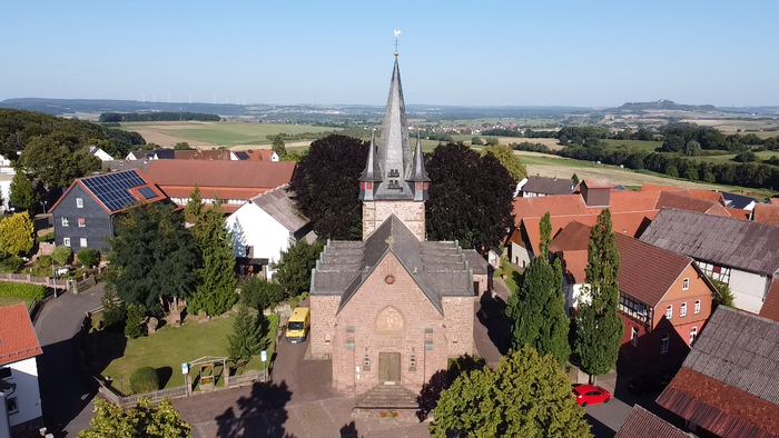 Ein Dorf mit Kirche und umgebenden Häusern in ländlicher Umgebung.