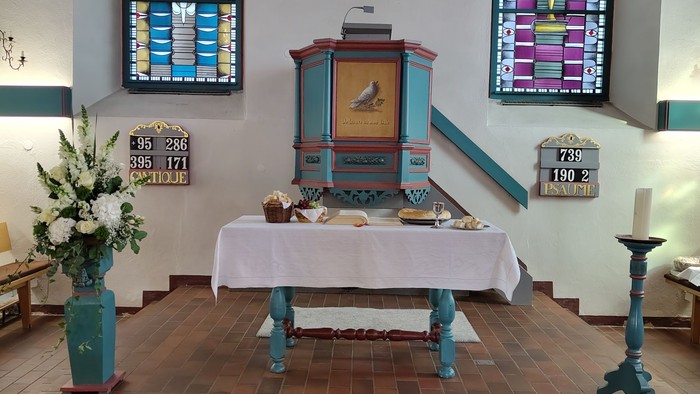 Idyllisches Kapelleninneres mit einem verzierten Altar, bunten Glasfenstern und schlichten Holzbänken.