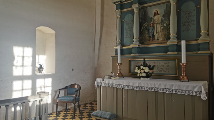 Alter i kirke med altertavle og blomsterarrangement