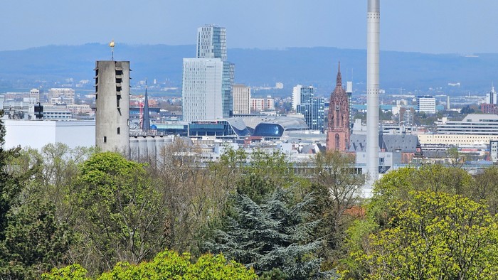 Stadtlandschaft mit hohen Gebäuden und Industrieanlagen, umgeben von Bäumen