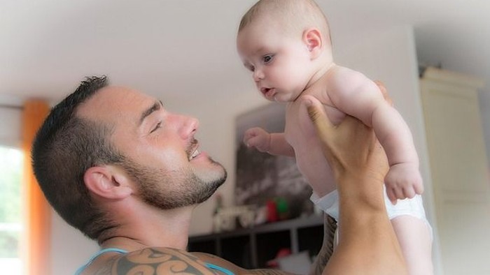 Ein Mann hält ein Baby in die Luft und lacht.