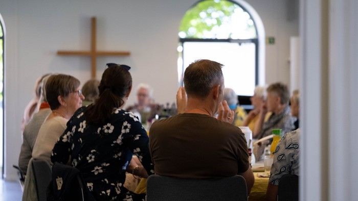 En gruppe mennesker sidder i en kirke og deltager i en gudstjeneste.