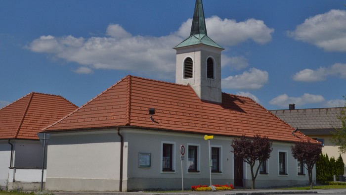 Kirche mit hohem Turm und rotem Dach unter blauem Himmel