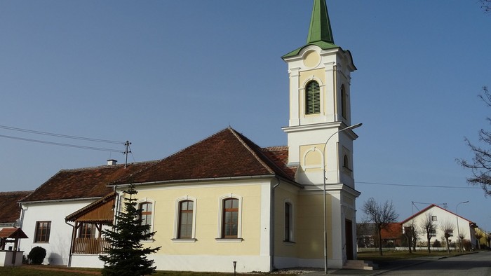 Kleine Kirche mit hohem Turm und grünem Dach in ländlicher Gegend