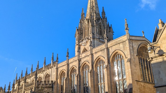 Großes gotisches Kirchengebäude mit hohem Turm und Menschen auf Straße