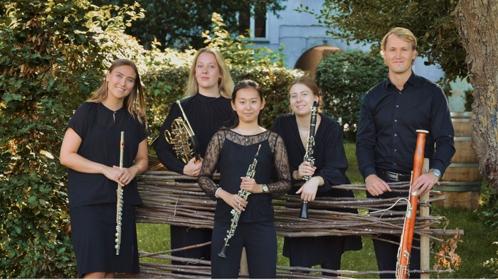 Et strygekvartet og en soloviolinist, der optræder udendørs i en fredfyldt have.