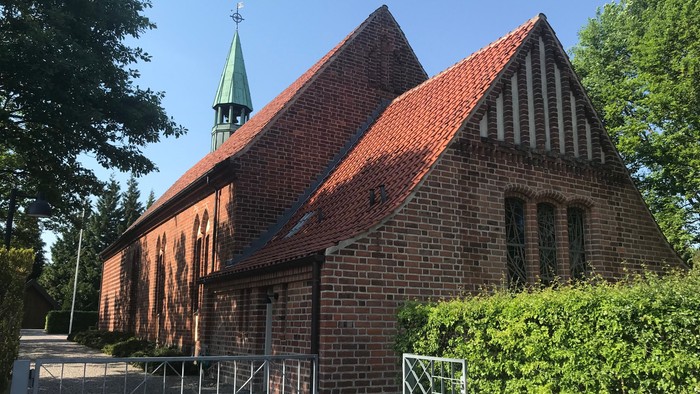 Røde teglkirke med spiret og murstakning.
