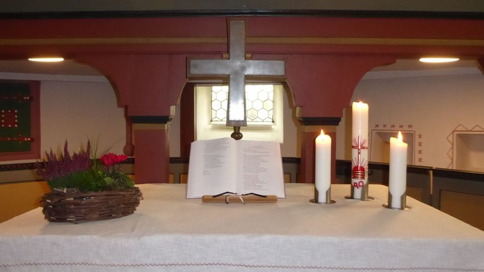 Altar mit Kreuz, Kerzen und Blumen in der Kirche