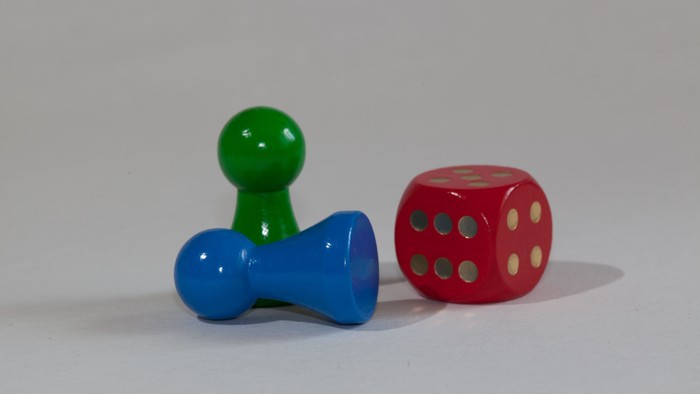 Zwei Spielfiguren und ein Würfel