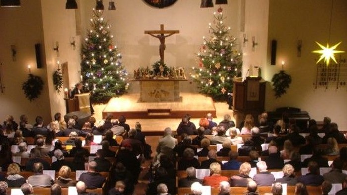 Gottesdienst in der Kirche mit vielen Gläubigen und Weihnachtsbäumen