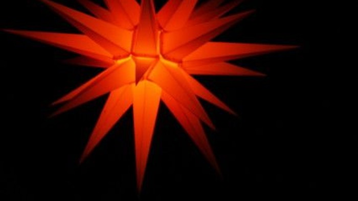 Ein leuchtender orangefarbener Stern vor schwarzem Hintergrund