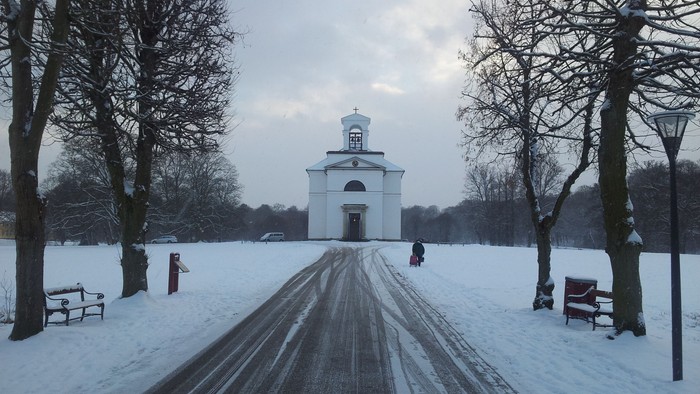 En snedækket vej med en lille kirke i baggrunden