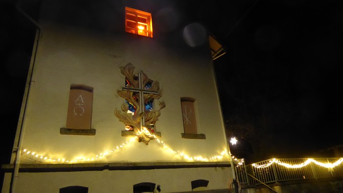 Gebäude mit beleuchtetem Kreuz und Lichtern, Nachtaufnahme