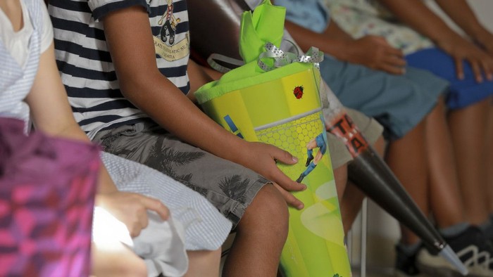 Ein Kind hält einen grünen Roboter, während es auf einem Stuhl sitzt.