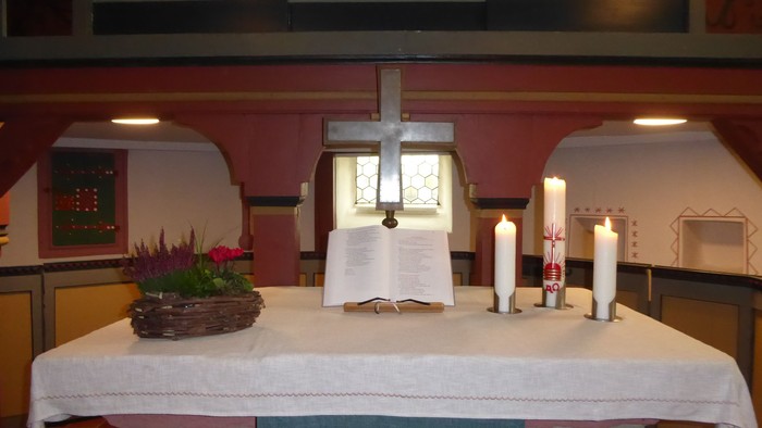Altar mit Kreuz, Kerzen und Blumen in der Kirche