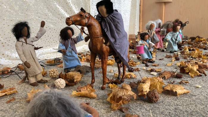 Miniaturpuppen und eine Pferdeszene, umgeben von verstreuten Nussschalen und Requisiten in einer kreativen Ausstellung.