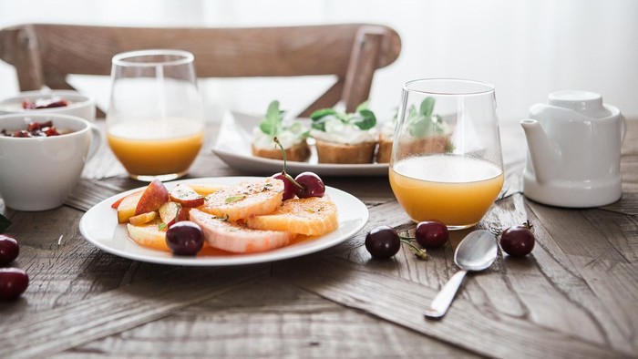 Ein Frühstückstisch mit Obst, Saft und Milch auf einem Holztisch