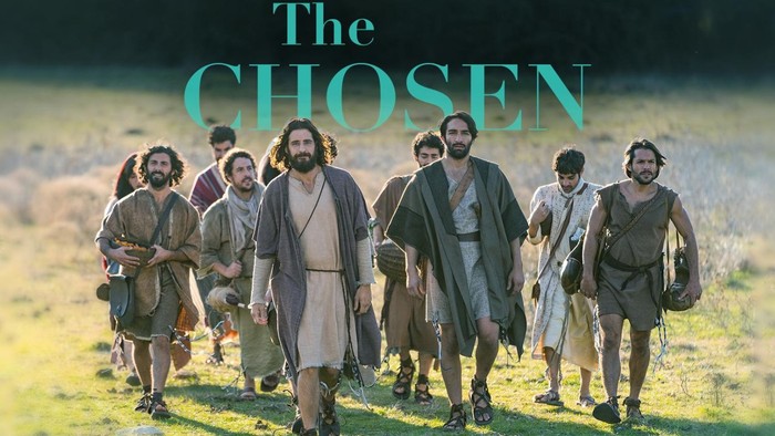 Eine Gruppe biblischer Figuren, darunter Jesus und seine Jünger, die gemeinsam durch ein Feld gehen.