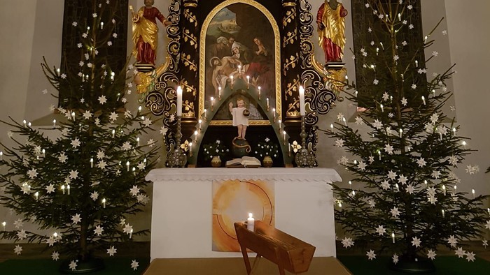 Weihnachtsdekoration in der Kirche mit Krippenszene und Tannenbäumen