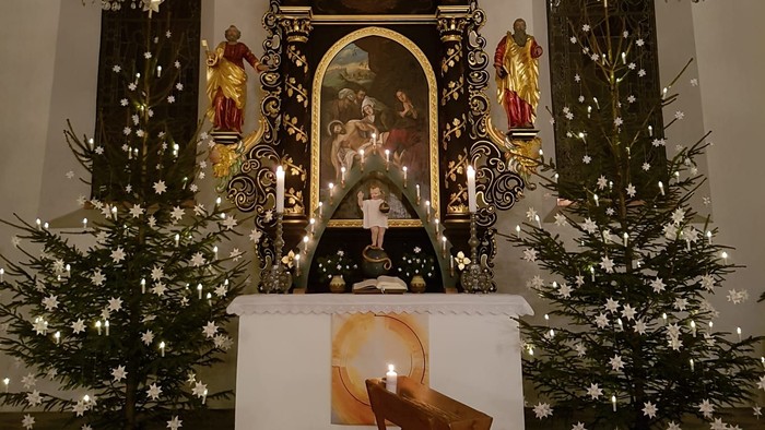 Weihnachtsdekoration in der Kirche mit Krippenszene und Tannenbäumen