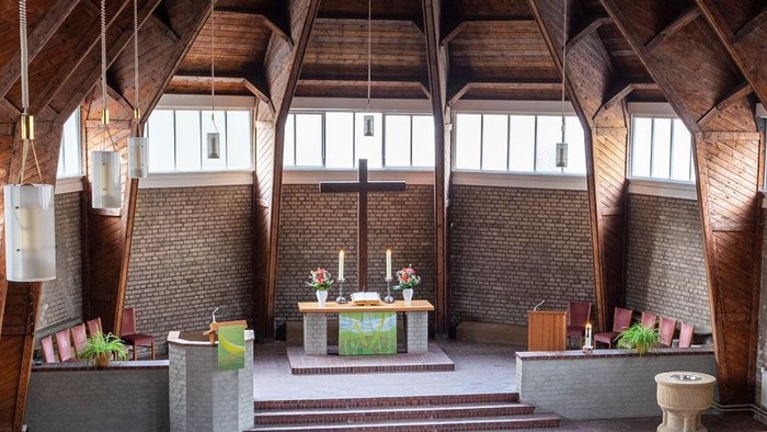 Ein moderner Wohnraum mit hohen Decken und großen Fenstern, eingerichtet mit Holz und grünen Akzenten.