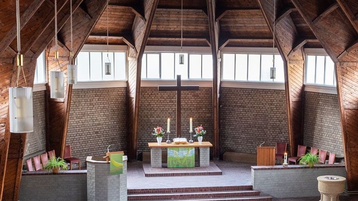 Ein moderner Wohnraum mit hohen Decken und großen Fenstern, eingerichtet mit Holz und grünen Akzenten.