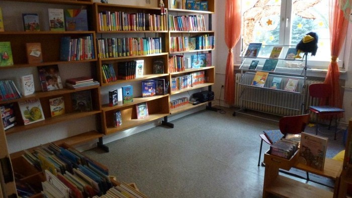 Bücherei mit vielen Regalen voller Bücher und einem Schreibtisch am Fenster