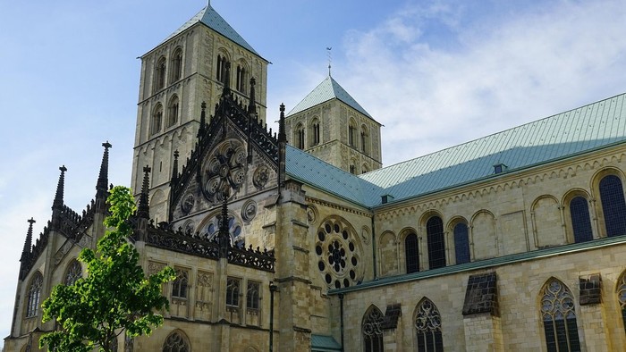Majestätische gotische Kathedrale mit kunstvollen Buntglasfenstern und hoch aufragenden Türmen unter einem klaren Himmel.