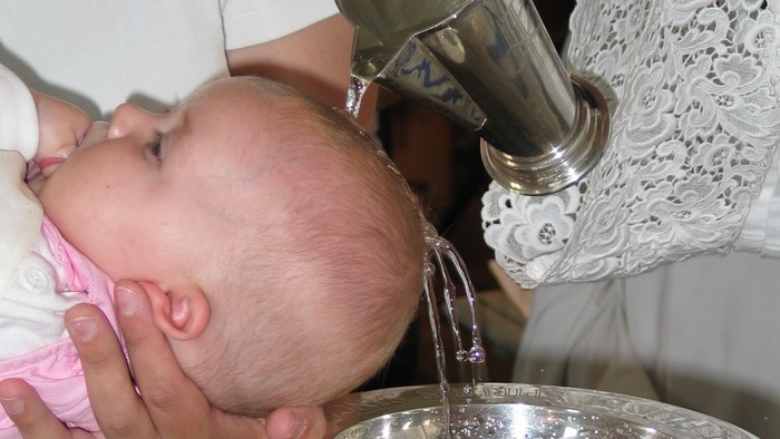 Ein Baby wird während eines zeremoniellen Rituals mit über den Kopf gegossenem Wasser getauft.
