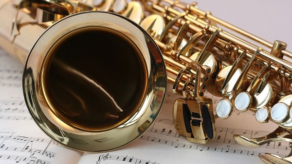 Ein goldenfarbener Saxophonmundstück liegt auf Notenblättern