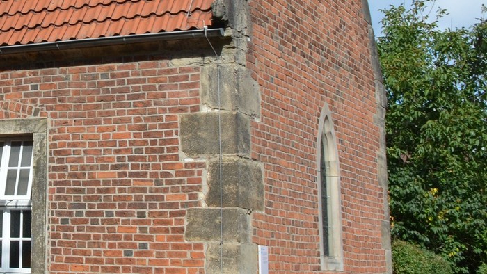 Kleine Backsteinkirche mit rotem Dach und Glockenturm.