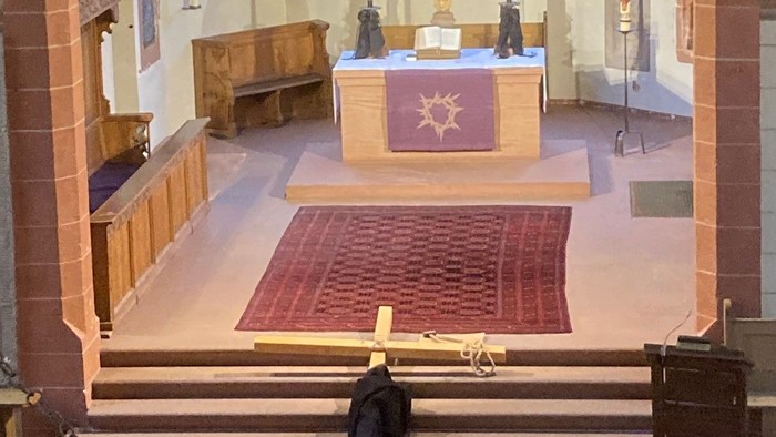 Ein Mann kniet in einer Kirche vor einem großen Holzkreuz.