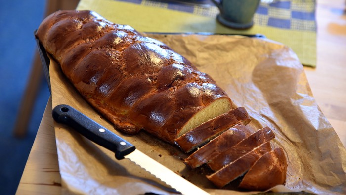 Goldbraun geschnittenes Brotlaib auf Backpapier mit einer Brotsäge daneben.