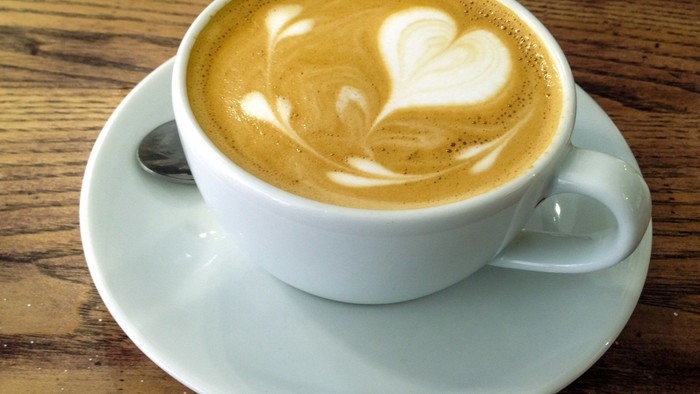 En lille kaffe i en hvid tæppe med mælkesæde i form af et hjerte på.