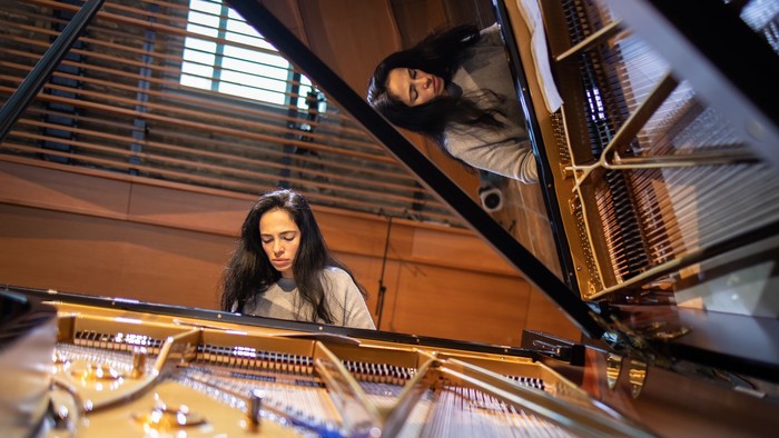 Zwei Personen, die ein großes, komplexes mechanisches Instrument beobachten und spielen, das einem Klavier ähnelt.