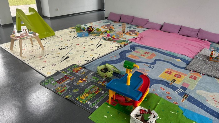 Heller Spielbereich mit thematischen Teppichen, Spielzeug und gemütlichen Sitzgelegenheiten für das fantasievolle Spielen von Kindern.