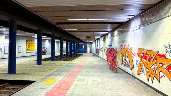 Unterirdischer Gang mit lebhaften Graffiti an den Wänden und gelben Sicherheitsmarkierungen auf dem Boden.