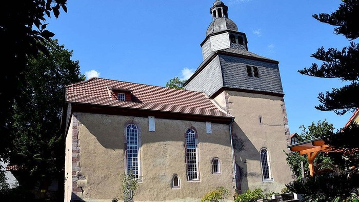 Kirchengebäude mit hohem Turm und rotem Dach unter blauem Himmel