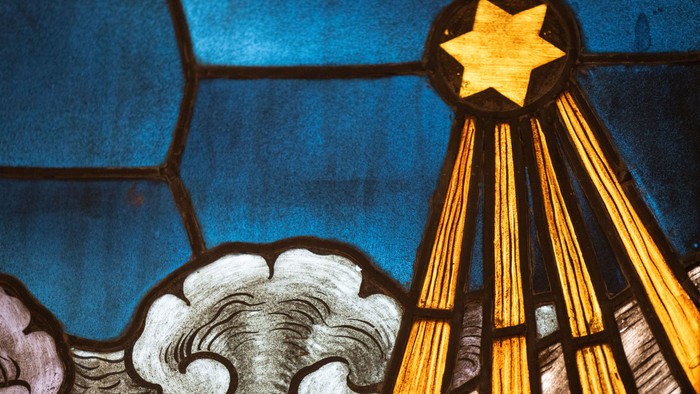 Buntglasfenster mit einem Davidstern und wolkenartigen Motiven in leuchtendem Blau und Gold.