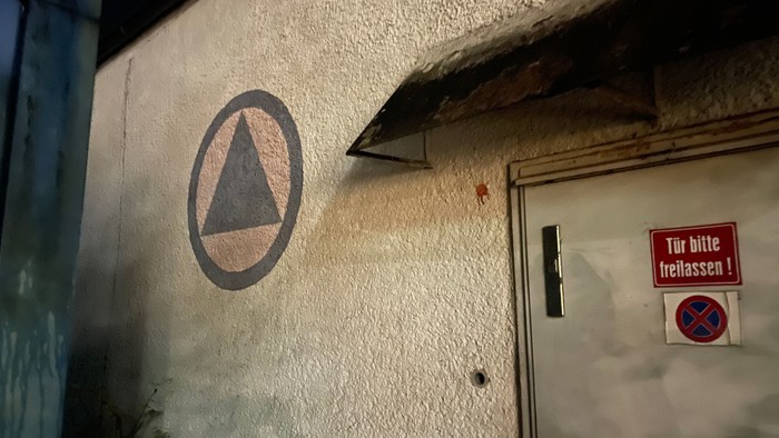 Eine Wand mit einem Dreieckssymbol und einem Schild auf Deutsch.