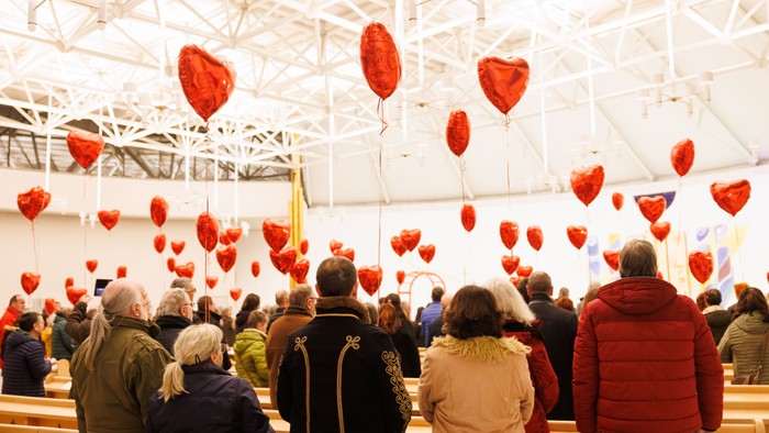 Viele Menschen in einem Raum mit vielen herzförmigen Ballons