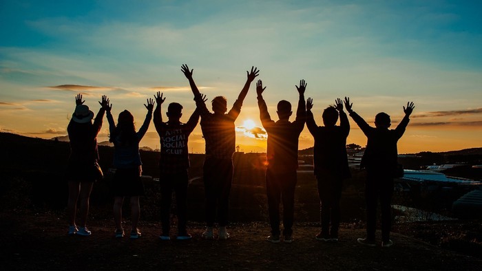 Eine Gruppe von Menschen feiert bei Sonnenuntergang