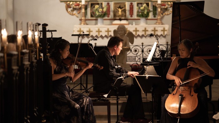 En trio spiller musik i kirke med violin, cello og piano