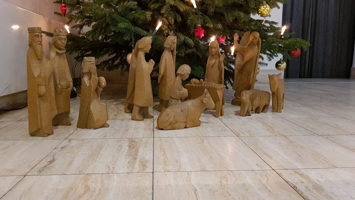 Unter dem Weihnachtsbaum steht eine Krippe mit Holzfiguren.