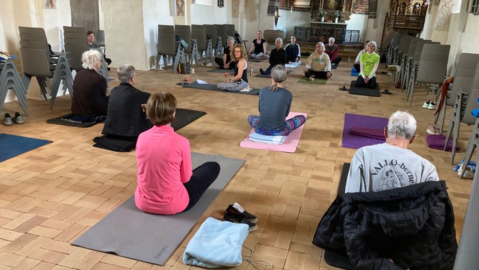 En gruppe mennesker udfører yoga i en historisk kirke.