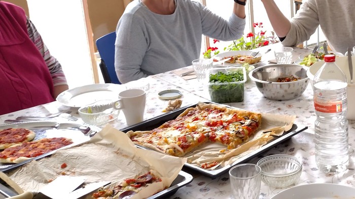 Eine Gruppe genießt gemeinsam eine Mahlzeit an einem Tisch, der mit verschiedenen Gerichten und Snacks gedeckt ist.